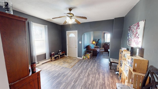 interior space with a textured ceiling, hardwood / wood-style floors, ceiling fan, and a baseboard heating unit