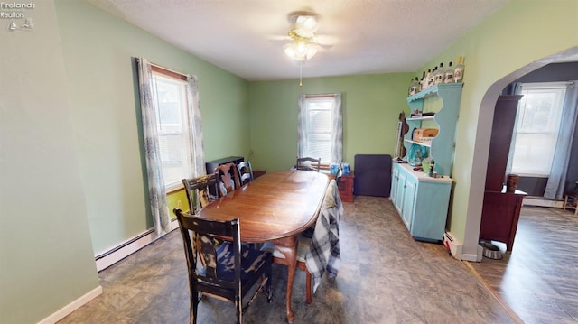 dining room featuring a wealth of natural light, ceiling fan, dark hardwood / wood-style floors, and baseboard heating