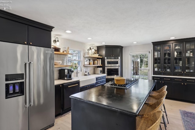 25 Edison, Milan, OH 44846 - kitchen with appliances with stainless steel finishes, dark cabinetry, a center island, open shelves, and light wood finished floors