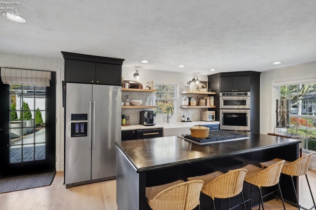 25 Edison, Milan, OH 44846 - kitchen featuring appliances with stainless steel finishes, open shelves, light wood-style flooring, a center island, and a sink
