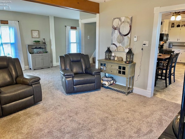 living room with light carpet, ceiling fan, beamed ceiling, and a wealth of natural light