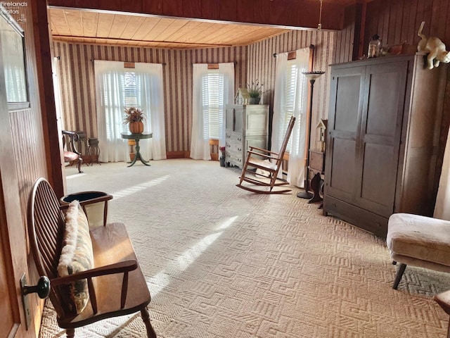 sitting room featuring wood ceiling, wood walls, and carpet flooring