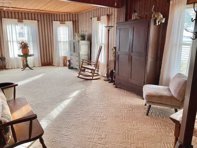 living area with light carpet, wooden walls, and wooden ceiling