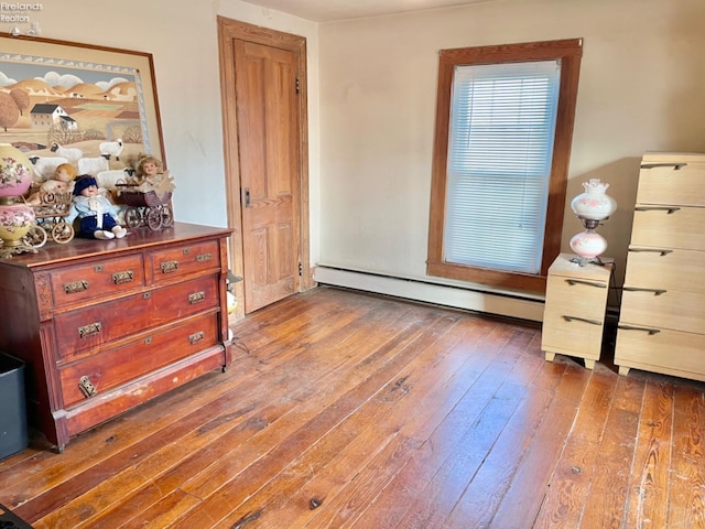 bedroom with baseboard heating and dark wood-type flooring