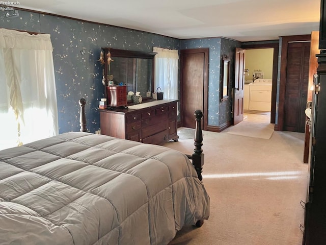 bedroom with connected bathroom, washing machine and clothes dryer, and light colored carpet