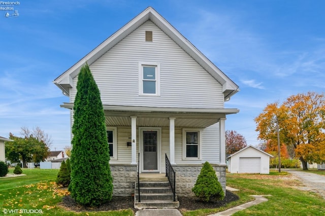 view of front of home with a front yard, a garage, an outbuilding, and a porch