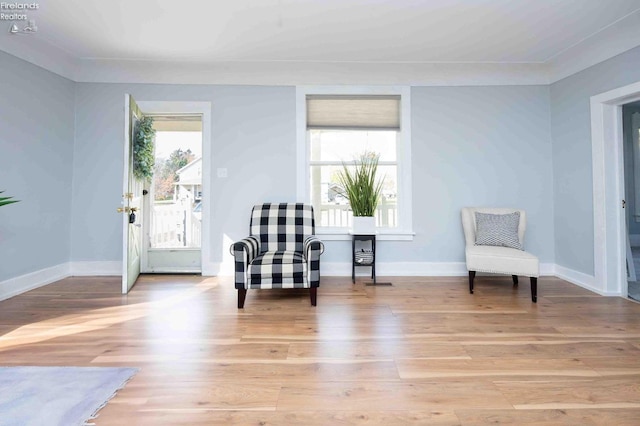 sitting room with ornamental molding and light hardwood / wood-style floors