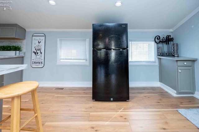 kitchen featuring light wood-type flooring, crown molding, gray cabinetry, and black refrigerator