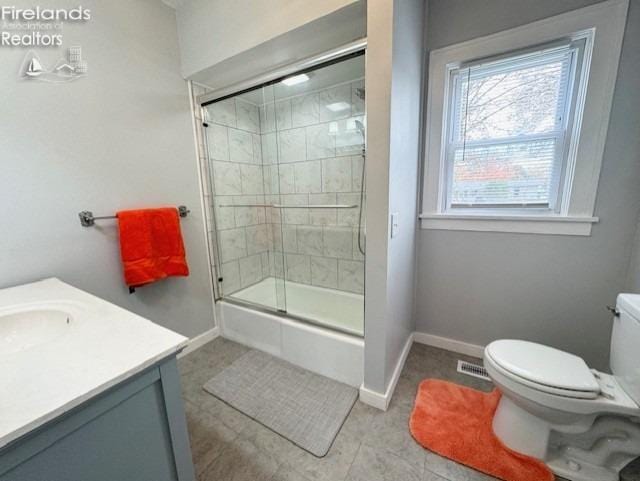 bathroom featuring toilet, vanity, tile patterned flooring, and a shower with shower door