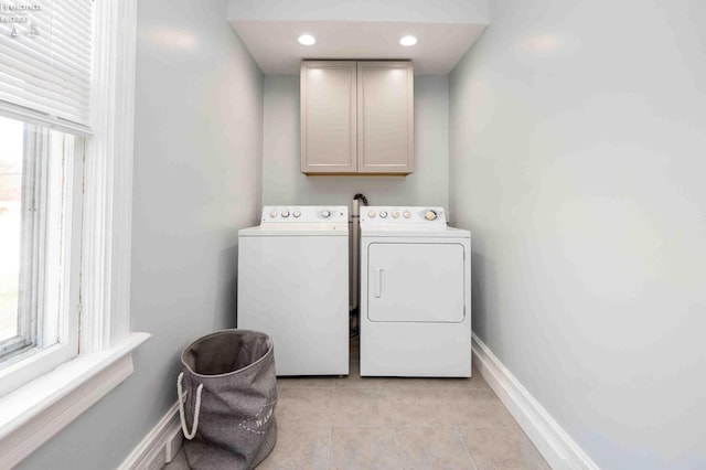 washroom with washing machine and dryer, cabinets, and light tile patterned floors