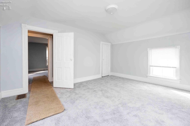 additional living space with vaulted ceiling and light carpet