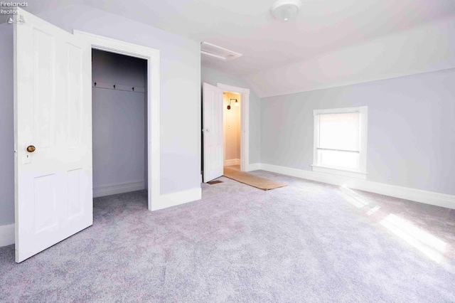 unfurnished bedroom featuring a closet, lofted ceiling, and light carpet