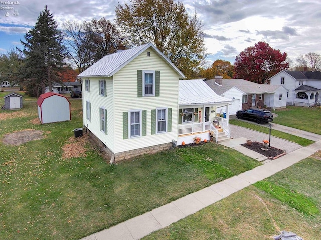 view of front of house featuring a porch, cooling unit, a front yard, and a storage unit