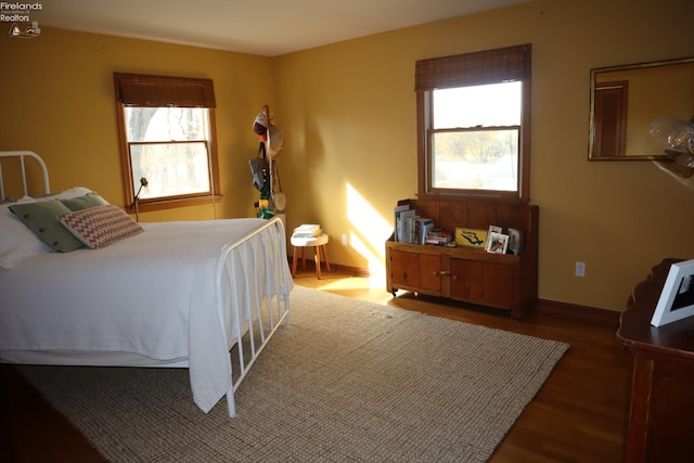 bedroom with multiple windows and dark hardwood / wood-style flooring