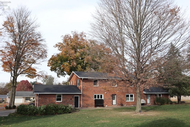 rear view of house featuring a garage and a lawn