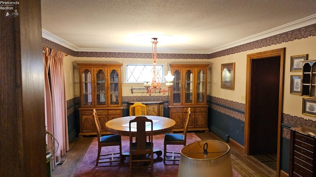 dining area featuring ornamental molding, a textured ceiling, a notable chandelier, and dark hardwood / wood-style floors