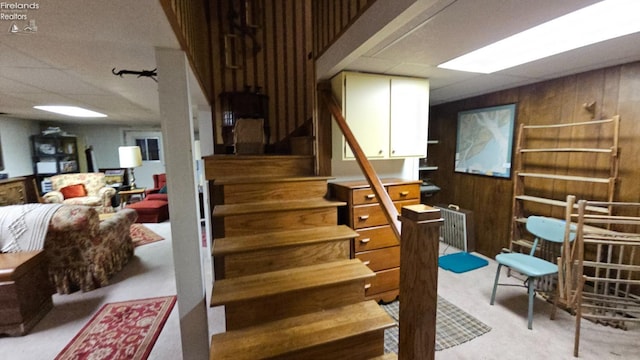 staircase featuring wooden walls and carpet flooring