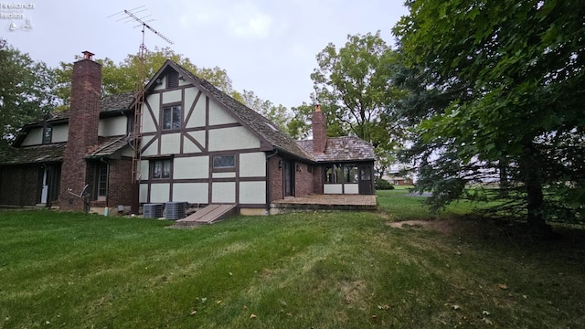 rear view of house featuring central AC unit and a yard