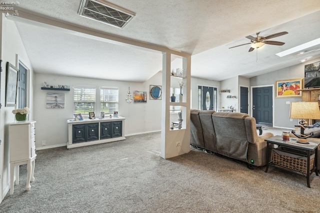 living room with a textured ceiling, carpet flooring, ceiling fan, and vaulted ceiling with skylight