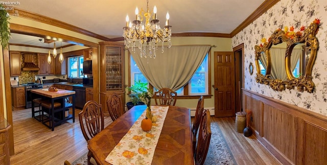 dining area featuring light hardwood / wood-style floors, a baseboard radiator, crown molding, and a notable chandelier