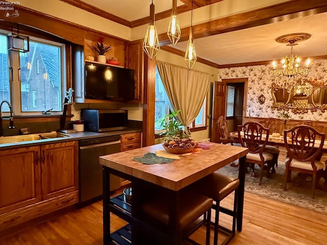 kitchen featuring stainless steel appliances, sink, pendant lighting, an inviting chandelier, and light hardwood / wood-style floors