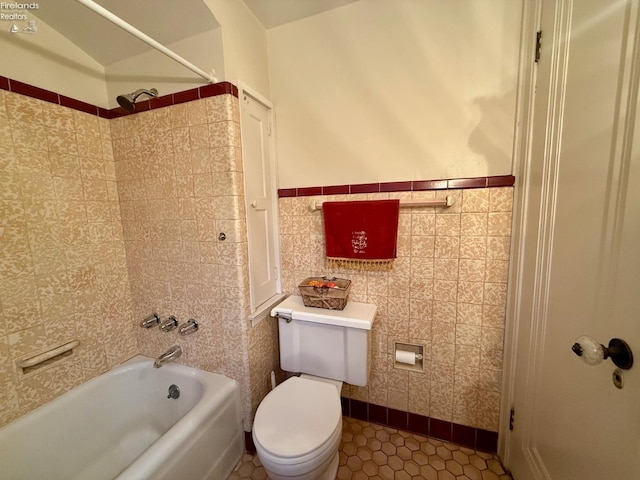 bathroom with tile patterned flooring, toilet, shower / bath combination, and tile walls