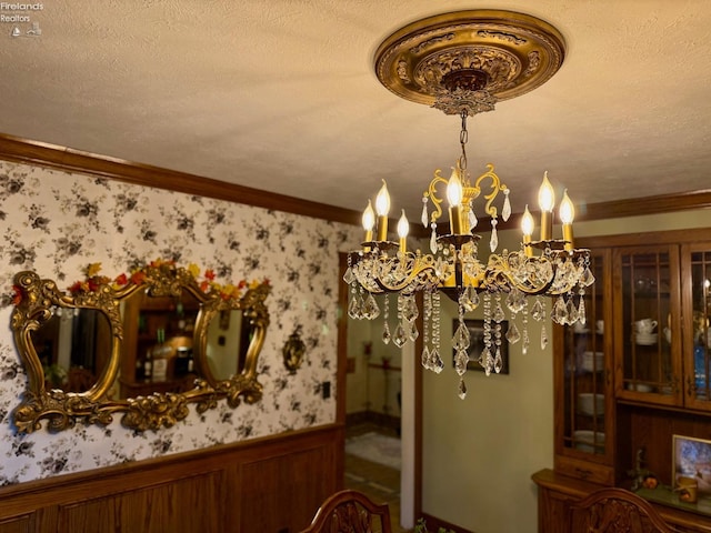 dining area with a textured ceiling, crown molding, a notable chandelier, and wood walls