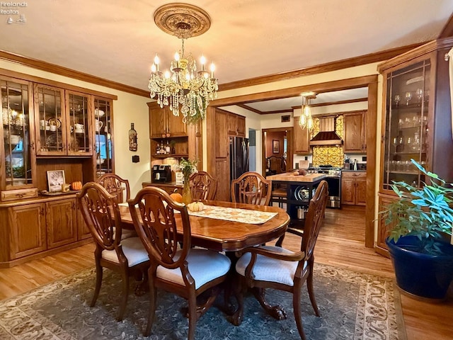 dining area featuring crown molding, a chandelier, and light wood-type flooring