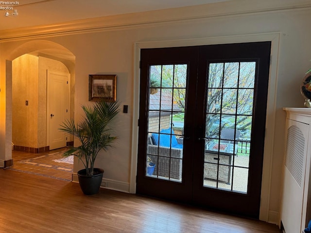 doorway with french doors, crown molding, and hardwood / wood-style floors