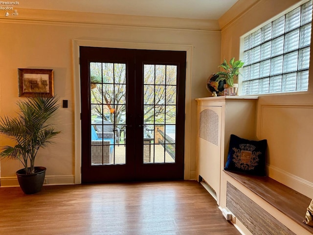 doorway to outside with french doors, ornamental molding, and light wood-type flooring