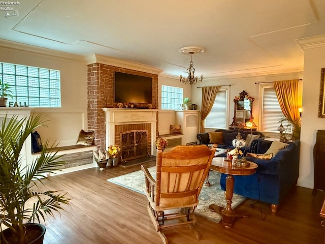 sitting room featuring a brick fireplace, plenty of natural light, ornamental molding, and hardwood / wood-style flooring