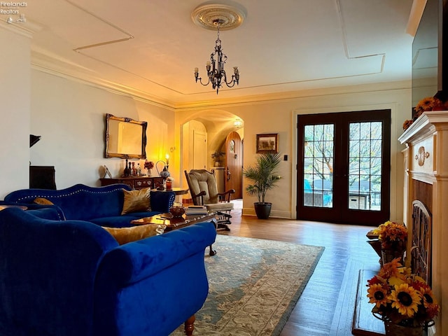 living room featuring crown molding, french doors, a chandelier, and hardwood / wood-style flooring