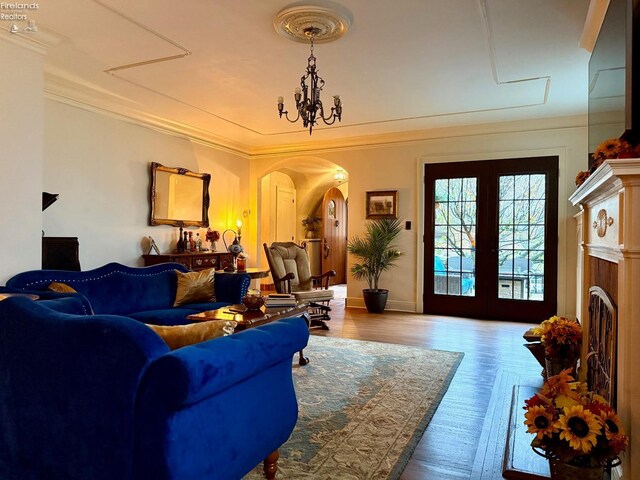 living room featuring crown molding, french doors, wood-type flooring, and an inviting chandelier