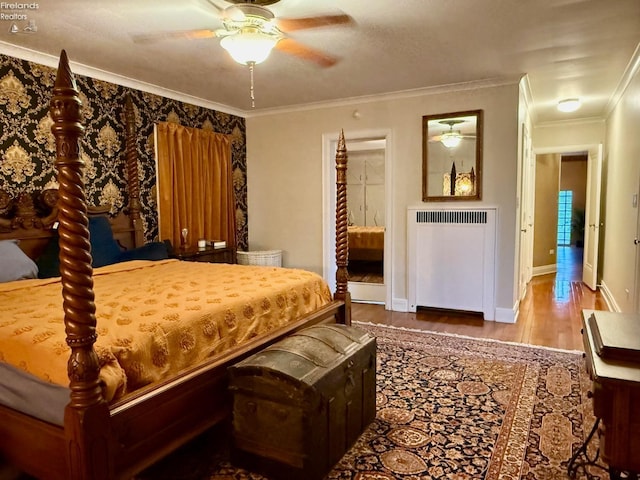 bedroom with ceiling fan, radiator heating unit, wood-type flooring, and ornamental molding