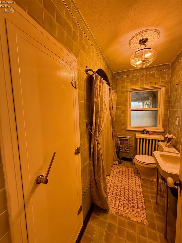 bathroom featuring a textured ceiling, toilet, and tile walls