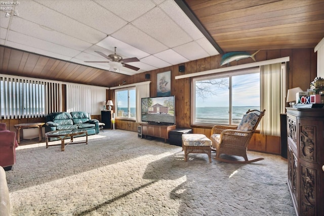 carpeted living room featuring wooden walls, a healthy amount of sunlight, ceiling fan, and vaulted ceiling