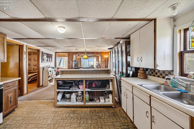 kitchen featuring white cabinets, a wealth of natural light, a paneled ceiling, and sink