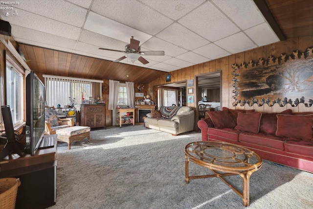 living room with carpet, a paneled ceiling, wood walls, lofted ceiling, and ceiling fan