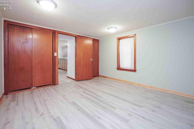 unfurnished bedroom featuring a closet, ornamental molding, and light wood-type flooring