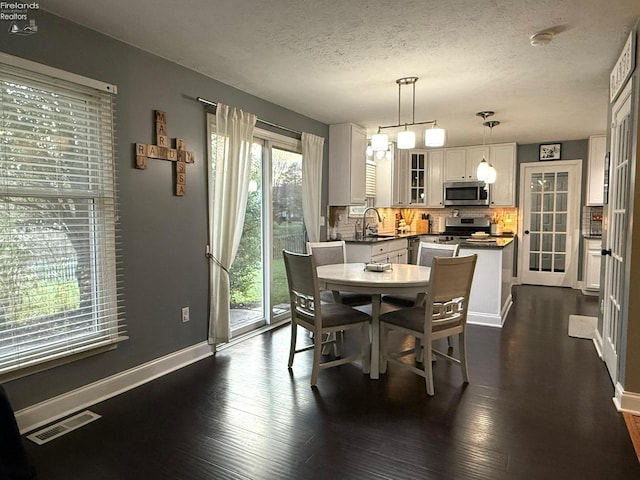 dining area featuring a textured ceiling, dark hardwood / wood-style flooring, and sink