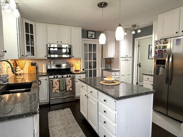 kitchen with white cabinets, appliances with stainless steel finishes, sink, and a kitchen island