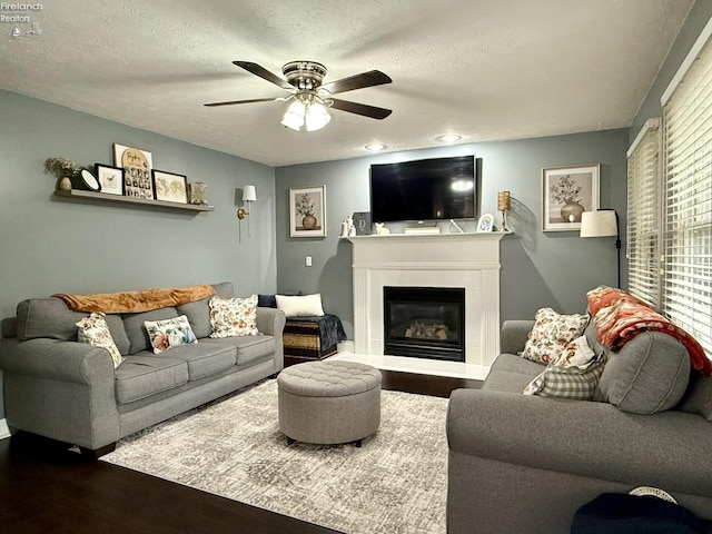 living room featuring a textured ceiling, dark hardwood / wood-style flooring, and ceiling fan