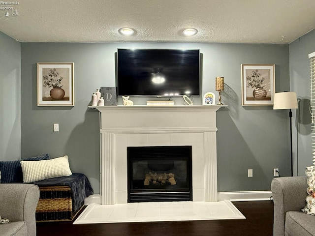 living room with a textured ceiling and a tile fireplace