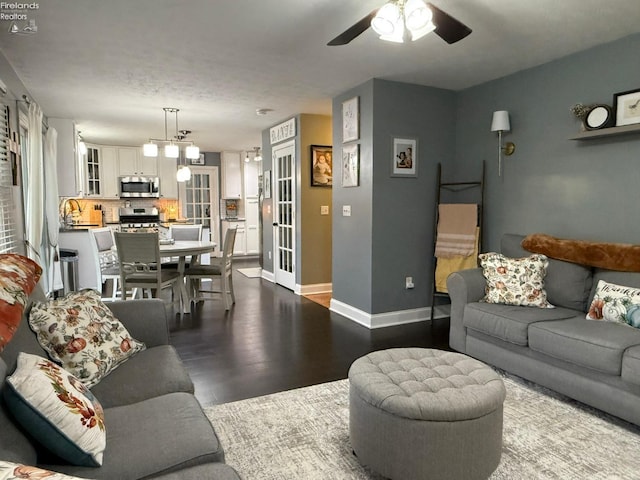 living room with ceiling fan with notable chandelier, hardwood / wood-style flooring, and sink