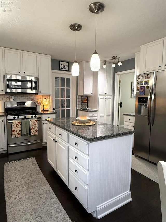 kitchen with white cabinets, decorative light fixtures, appliances with stainless steel finishes, and a center island