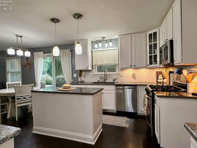 kitchen with a kitchen island, white cabinets, decorative light fixtures, and stainless steel appliances