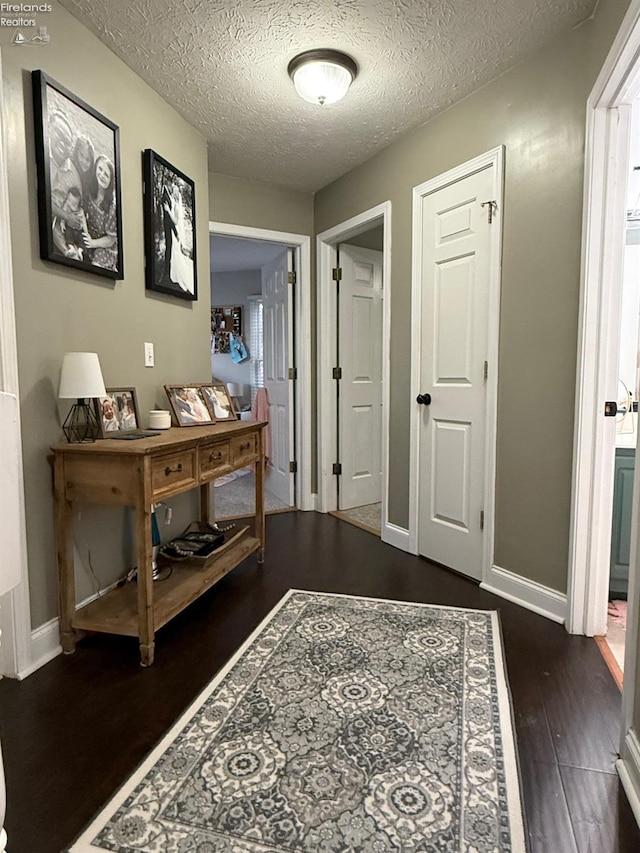 hallway with a textured ceiling and dark hardwood / wood-style flooring