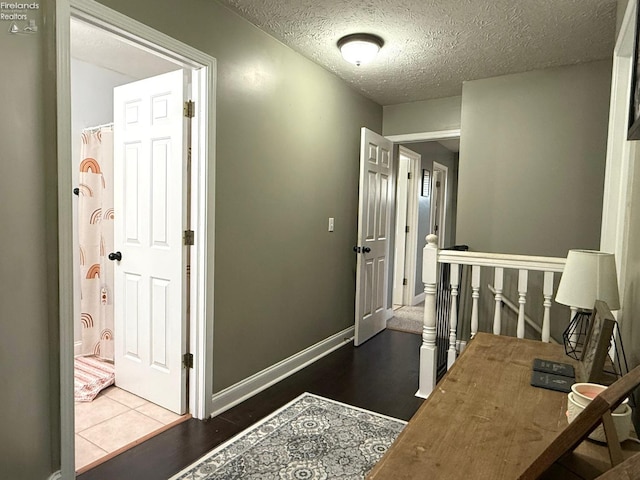 hallway with dark wood-type flooring and a textured ceiling