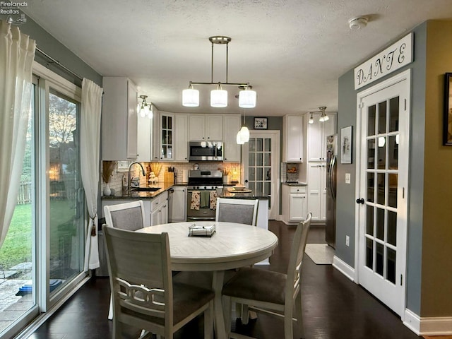 dining area featuring dark wood-type flooring, sink, and a textured ceiling