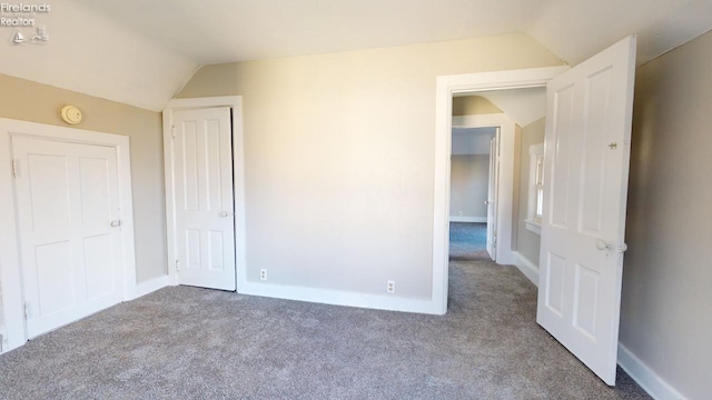 unfurnished bedroom featuring carpet and vaulted ceiling